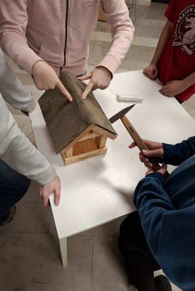 Fotografie zachycuje děti vyrábějící krmítko v kroužku